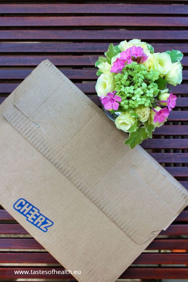 A picture of a parcel from Cheerz and a cream and pink flower arrangement.