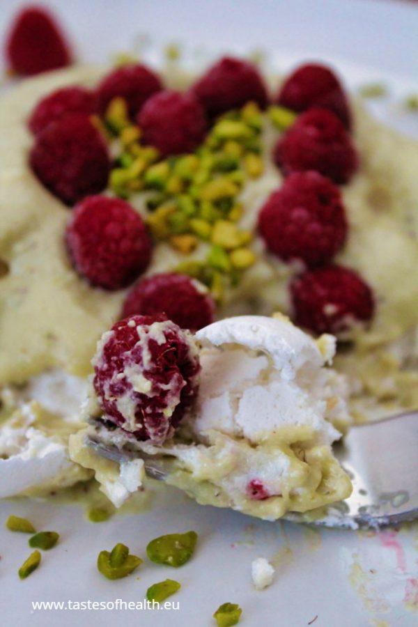 An image for the post: Vegan Meringue Recipe. A piece of aquafaba meringue with pistachio cream and raspberries on a fork.