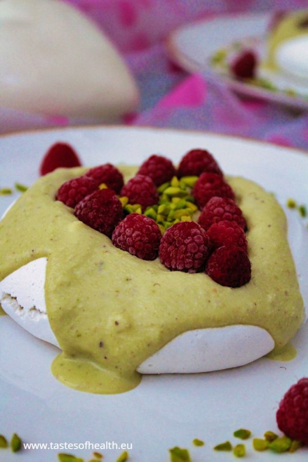 An image for the post: Vegan Meringue Recipe. An aquafaba meringue with pistachio cream and raspberries arranged in a shape of a heart.